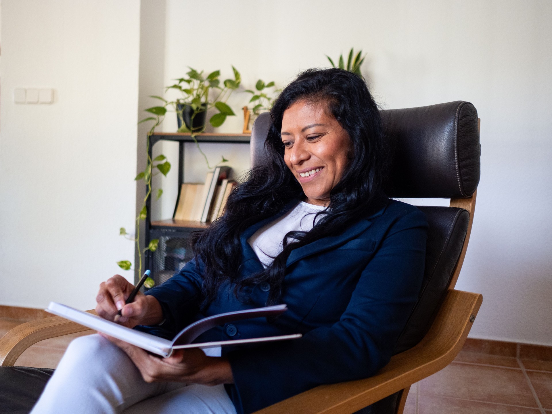 Mexican psychologist and coach smiles to a patient while writing in a notebook